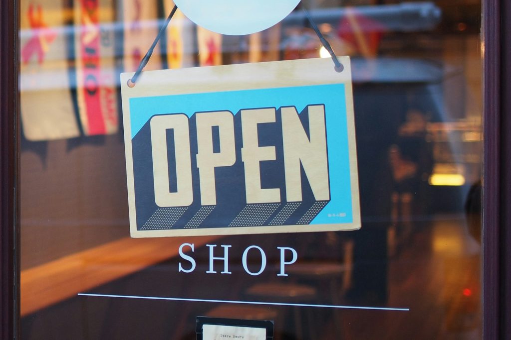 "open" sign hanging in a shop window