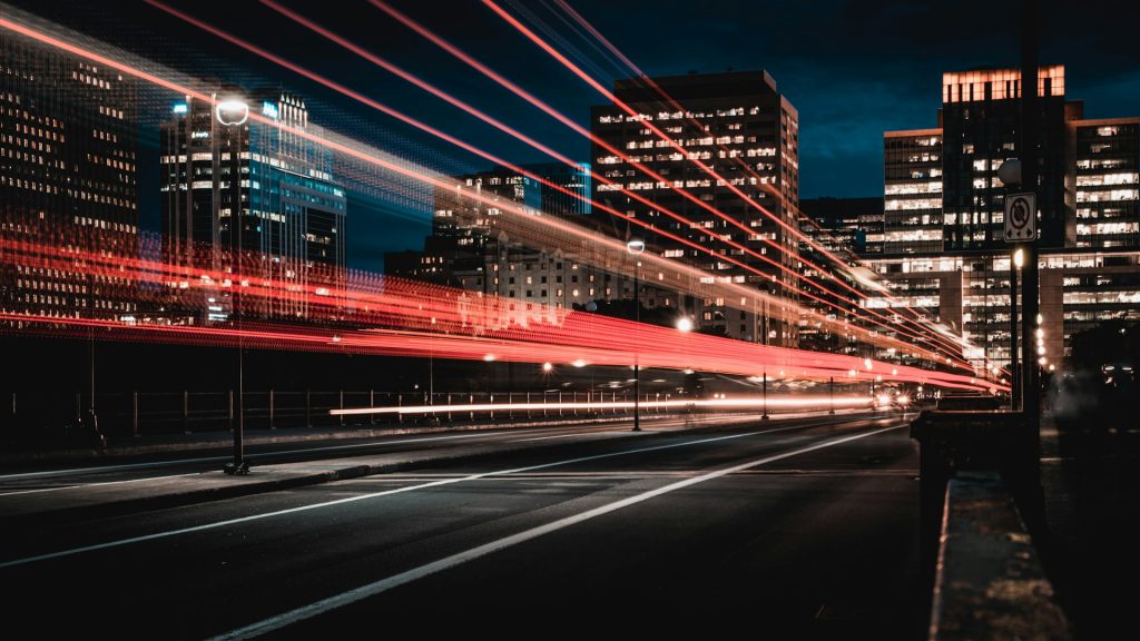 A city street with a vehicle's light streaks racing by