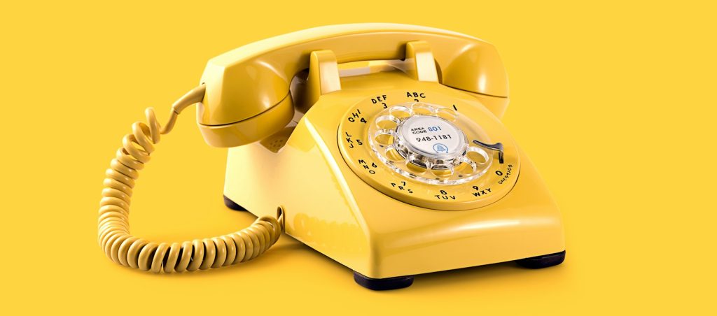 yellow rotary phone in front of a yellow background