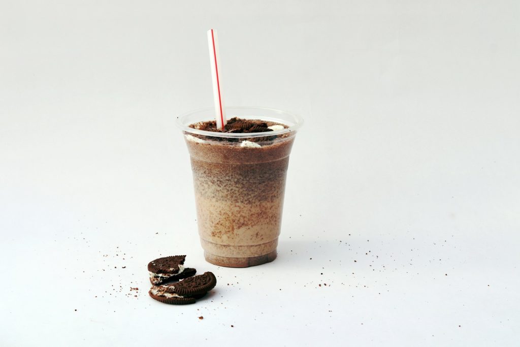 a broken Oreo cookie next to a large cookies n' cream drink